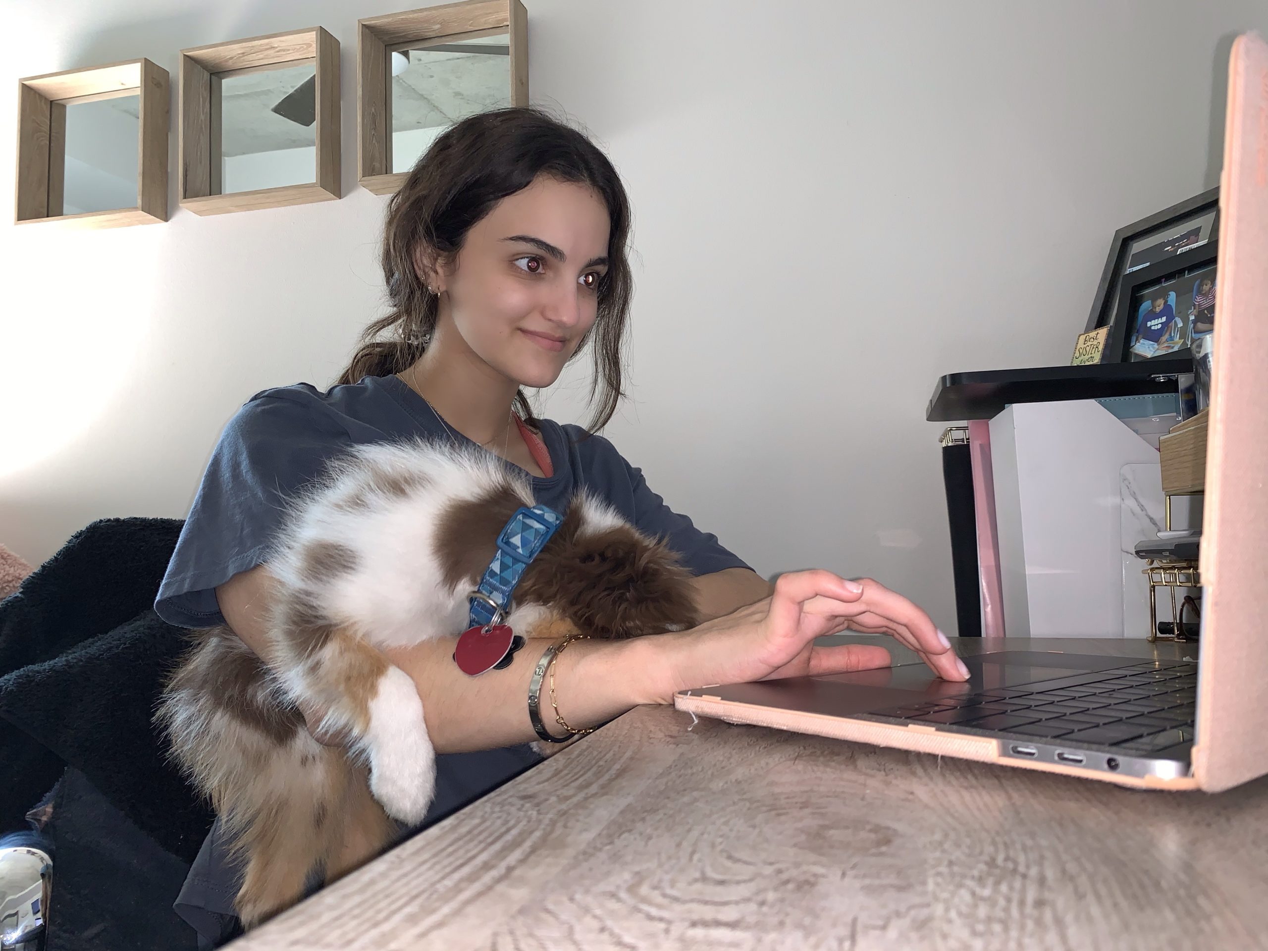 Madison Olson types at her laptop with her dog, Winston