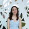 Young woman smiles in front of abstract wall